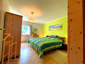 ein Schlafzimmer mit einem Bett in einem Zimmer mit gelben Wänden in der Unterkunft window on the green in Poschiavo
