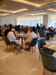 een groep mensen die aan tafel zitten in een restaurant bij Dolphin Continental Hotel in Koeweit