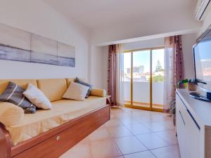 un soggiorno con un divano e una grande finestra di AL - Apartamento Quinta do Romão a Quarteira Altre 13 foto
