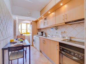 - une cuisine avec des placards en bois, une table et un évier dans l'établissement AL - Apartamento Quinta do Romão, à Quarteira