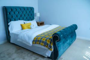 a large bed with a blue headboard and yellow pillows at Millward Homes in Bletchley