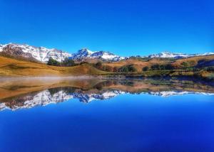 vistas a un lago con montañas en el fondo en Gooderson Drakensberg Gardens Golf & Spa Resort, en Drakensberg Garden