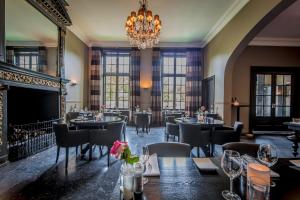 a restaurant with tables and chairs and a chandelier at Fletcher Landgoedhotel Renesse in Renesse