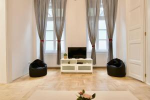 een woonkamer met een tv en twee zwarte stoelen bij Standard Apartment by Hi5 - Múzeum 5 in Boedapest