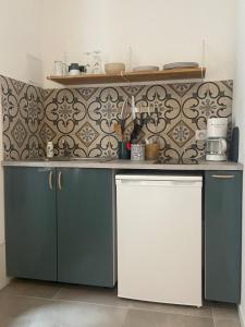 een keuken met blauwe kasten en een witte koelkast bij Studio - Cœur de Ville in Sérignan