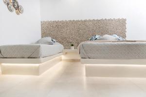 2 camas en un dormitorio con paredes blancas y suelo blanco en Katerina Roza Studios, en Naxos Chora