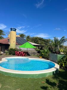 una piscina con una sombrilla verde y una casa en Casa verde praia do Piruí 100 mts da praia 750 mts de área privativa, en Camaçari