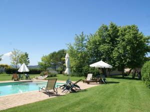 einen Pool mit Stühlen und Sonnenschirmen neben einem Hof in der Unterkunft Nice apartment with pool and beautiful garden in Montone