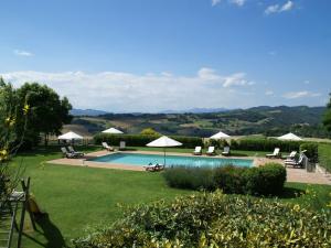 una piscina con sillas y sombrillas en un jardín en Nice apartment with pool and beautiful garden, en Montone