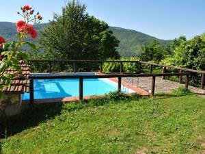 a pool in a field with a fence and flowers at Lovely Holiday Home with private pool in San Marcello Pistoiese