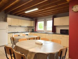 eine Küche mit zwei Tischen in einer Küche mit einer Uhr in der Unterkunft Modern Cottage in Baugnez Malmedy with Sauna in Arimont