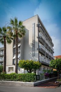 a building with palm trees in front of it at Corallo Wellness Hotel in Diano Marina