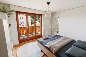 ein Schlafzimmer mit einem Bett und einem Balkon in der Unterkunft Logement chaleureux au coeur de la station in Crans-Montana
