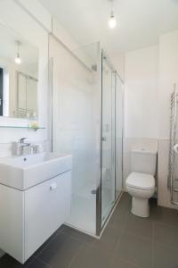 ein weißes Bad mit einem WC und einer Glasdusche in der Unterkunft 4 Bedrm House Greater London in London