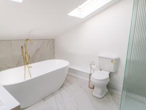 a white bathroom with a tub and a toilet at The Workshop in Northallerton