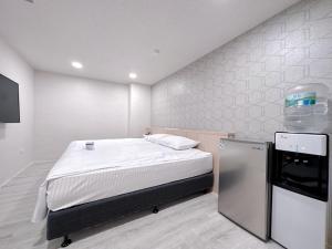 a small room with a bed and a refrigerator at 夢境旅-智能自助旅店 in Zhongli