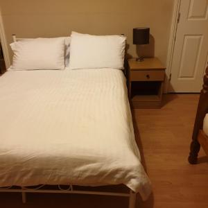 1 cama con sábanas blancas y almohadas en una habitación en Homeleigh Apartments- Isle of Wight, en Ryde