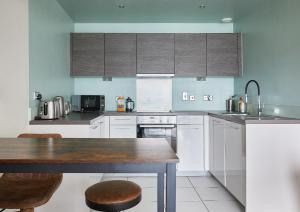 a kitchen with white cabinets and a wooden table at The Glassworks by Ritual Stays in Hemel Hempstead +26 photos