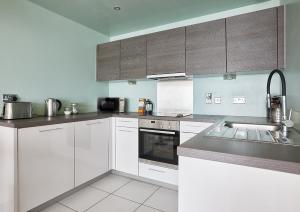 a kitchen with white cabinets and a sink at The Glassworks by Ritual Stays in Hemel Hempstead