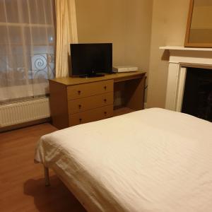 Dormitorio con cama y tocador con TV en Homeleigh Apartments- Isle of Wight, en Ryde