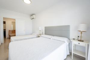 アルクーディアにあるVilla Garballo Alcudia - Sea Frontの白いベッドルーム(ベッド2台、テーブル付)