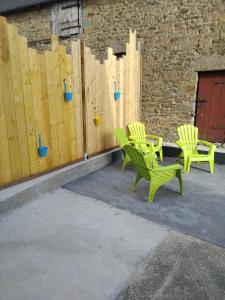 dos sillas verdes sentadas junto a una valla de madera en Gîte familial, en Plouguenast Langast