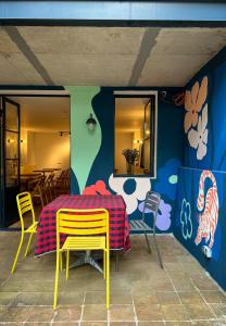 a table and chairs on a patio with a colorful wall at Black Tomato Hostel Kutaisi in Kutaisi