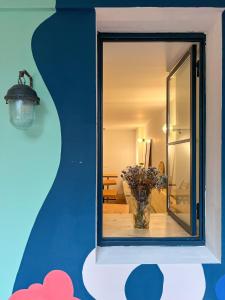 a window with a vase of flowers in a room at Black Tomato Hostel Kutaisi in Kutaisi