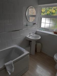 a bathroom with a tub and a sink and a mirror at St Quintin Arms in Harpham