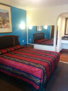 Habitación de hotel con cama grande y espejo en Sunshine Motel, en San Bernardino