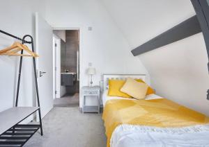 um quarto com uma cama com almofadas amarelas em The Chapel Cottage by Ritual Stays em Hemel Hempstead