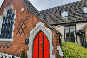 Una casa de ladrillo con una puerta roja. en The Chapel Cottage by Ritual Stays en Hemel Hempstead