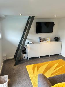 a living room with a tv and a ladder at The Bubble Hideaway - A Little Oasis near the Sea in Whitstable