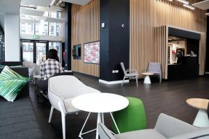 una persona seduta a un tavolo in una stanza con tavoli e sedie di Beckett House near Dublin City Centre a Dublino