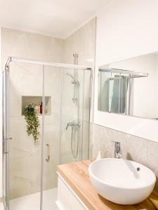 een witte badkamer met een wastafel en een douche bij Olea apartments in Pobegi
