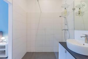 ein weißes Bad mit einem Waschbecken und einer Dusche in der Unterkunft Modernes Apartment in Berlin in Berlin