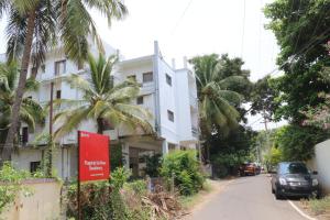 a street in front of a white building with palm trees at Shree SaiRenu near maruthamalai and bharathiyar univ and on the way to Adiyogi Isha Yoga centre in Marudhamalai