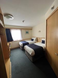 a hotel room with two beds and a window at Weald of Kent Golf Course and Hotel in Headcorn