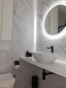 a white bathroom with a sink and a mirror at Apartman Nika Makarska in Makarska