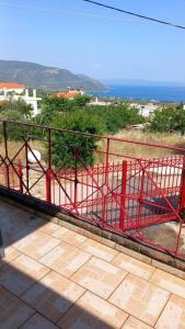 a red fence on a balcony with a view of the ocean at AMAZING VIEW IN ANTHIDONA in Loukísia