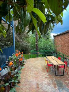 um pátio com uma mesa de madeira, cadeiras e flores em Black Tomato Hostel Kutaisi em Kutaisi