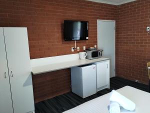 a kitchen with a counter with a microwave and a tv on a brick wall at Junction Motel Wagga in Wagga Wagga