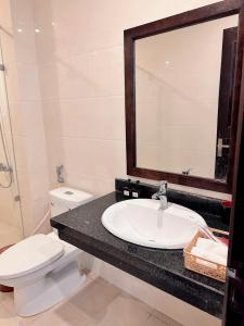 a bathroom with a sink and a toilet and a mirror at Tuần Châu - Phương Đông Motel Hạ Long in Ha Long