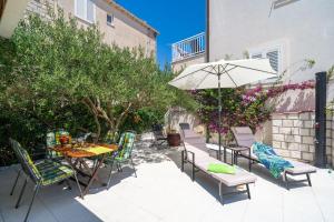 een patio met een tafel en stoelen en een parasol bij Apartments Villa Key in Cavtat