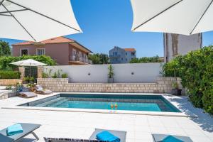 una piscina en un patio trasero con sombrillas en Apartments Villa Key en Cavtat