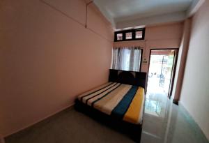 a small bedroom with a bed and a window at The Gardenview in Guwahati