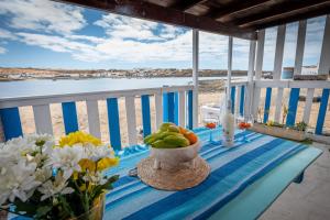 uma mesa com uma tigela de frutas e flores numa varanda em Cabin in front of idyllic majanicho beach em Majanicho