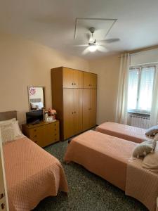 a bedroom with two beds and a cabinet and a television at La Maisonette Apartment with terrace - 2min to outlet in Serravalle Scrivia