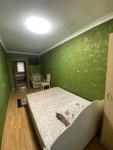 um quarto com uma cama e uma parede verde em 3 комнатная квартира Аэропорт em Turksib