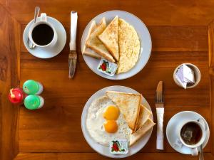 two plates of eggs and toast on a table with coffee at Double-G Guest House in Nusa Penida